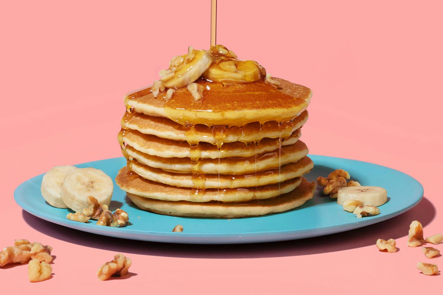 stack of banana bread pancakes on turquoise plate topped with maple syrup