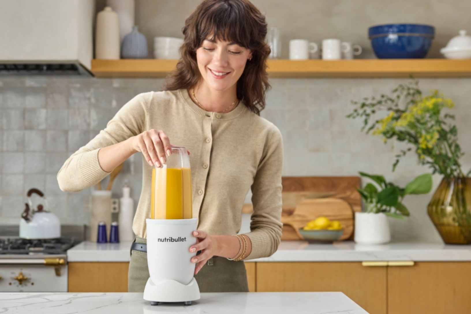 woman blending an orange smoothie in a white nutribullet personal blender