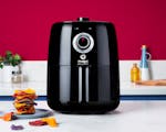 Product preview 1 of 9. Thumbnail of NEW Black nutribullet Air Fryer next to chips on kitchen counter on pink background.