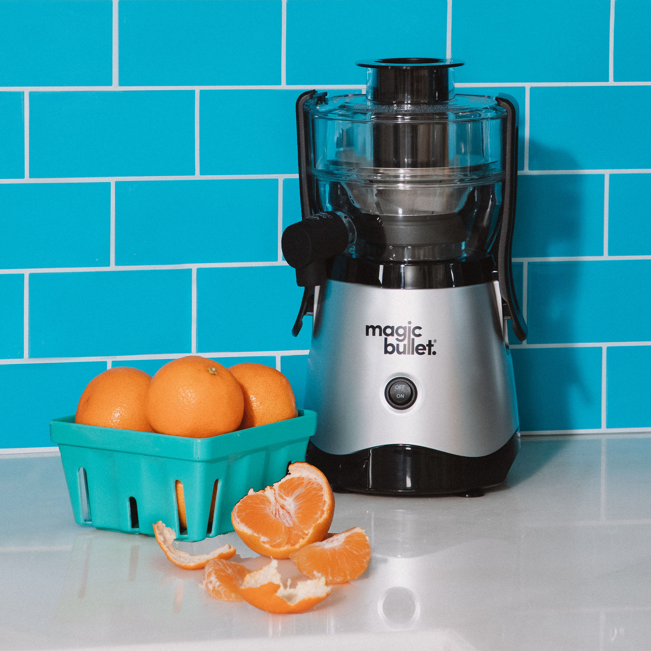 magic bullet Mini Juicer on kitchen countertop with turquoise background alongside fresh oranges