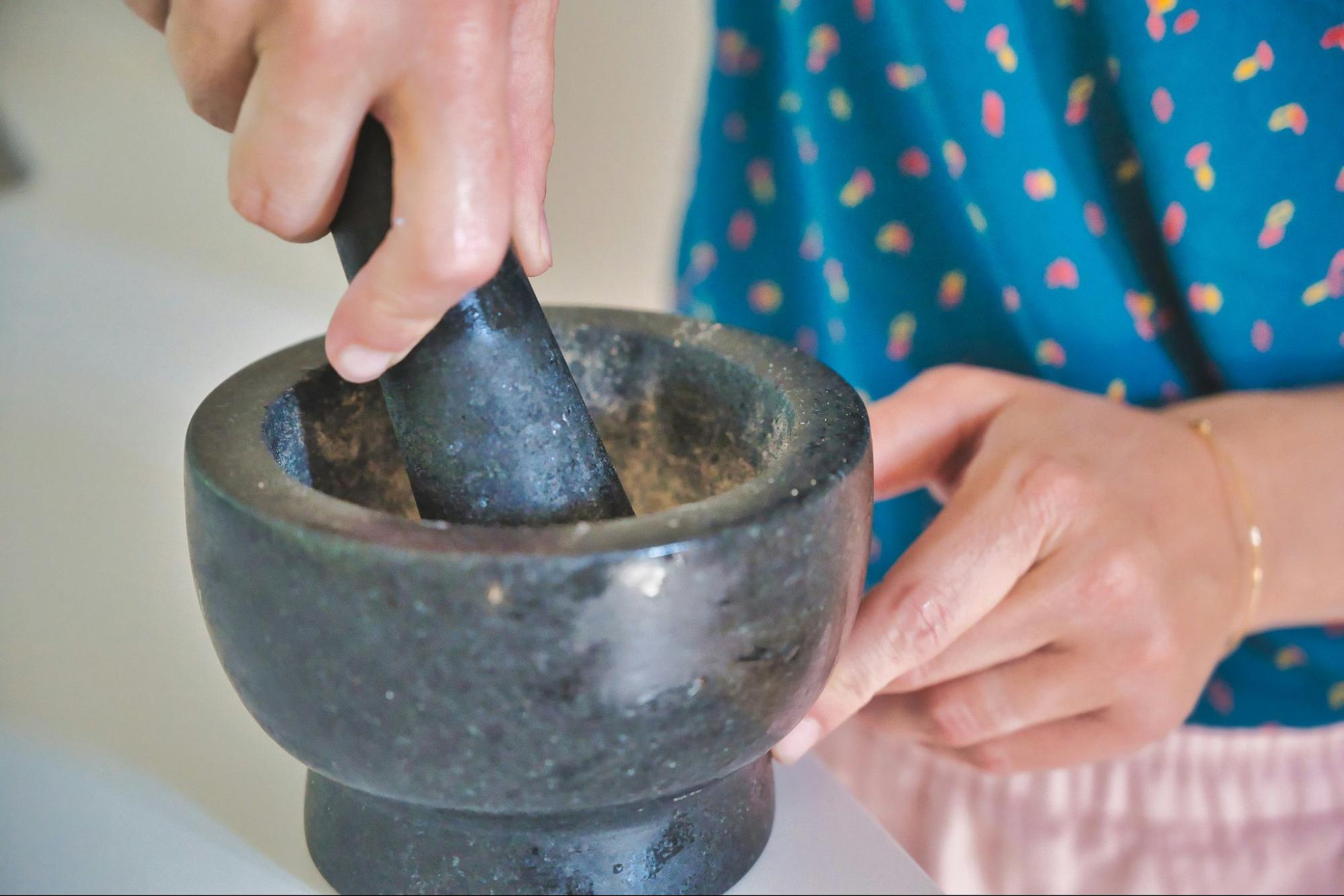 using mortar and pestle to grind coffee beans