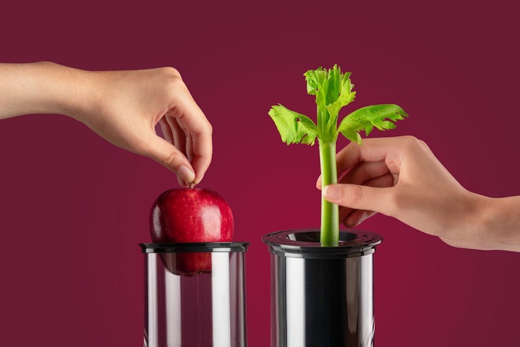 an apple and celery stalk being inserted into the NutriBullet Juicer chutes