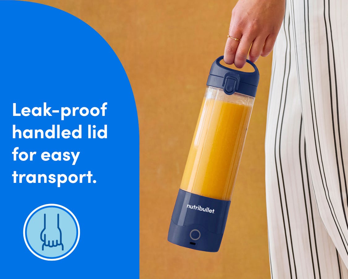 A closeup of a woman's hand, carrying the portable blender near her hip. She is wearing loose, striped white pants. A blue panel to the left of the image reads: "Leak-proof handled lid for easy transport". A circular icon beneath the text shows an illustration of a hand gripping the handled lid of the blender.