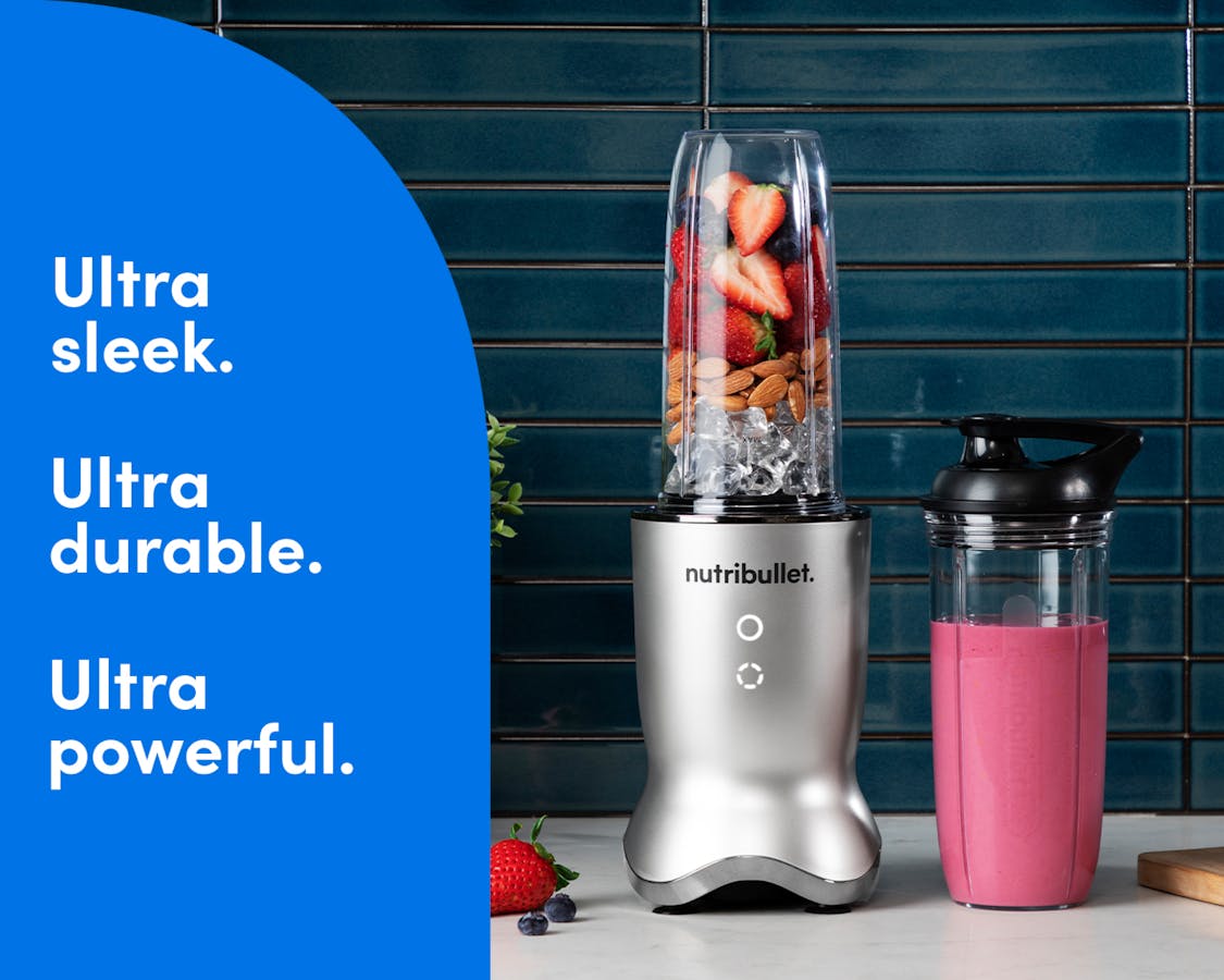 The silver nutribullet Ultra rests on a kitchen counter filled with fruit, ice, and nuts. The nutribullet Ultra cup is next to it, filled with a pink smoothie. Text on the image reads: Ultra sleek. Ultra durable. Ultra powerful.