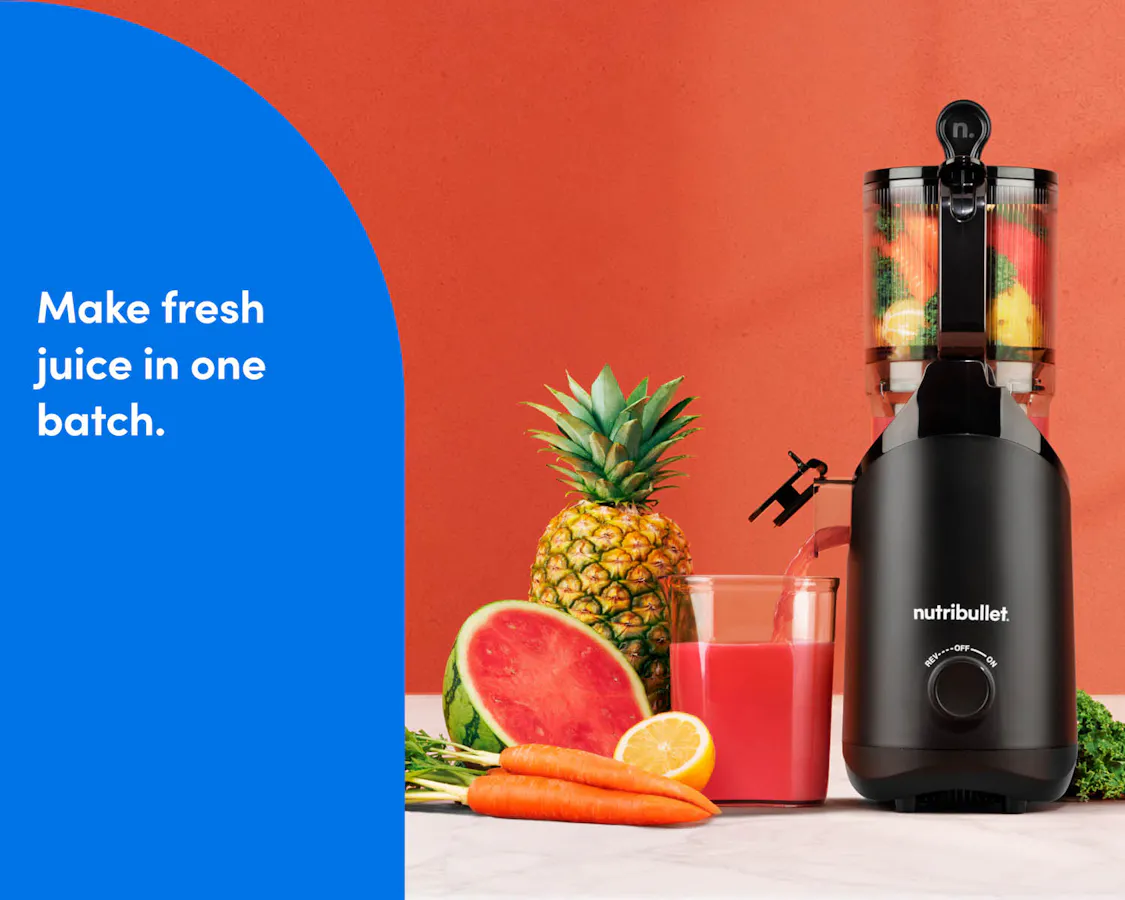 nutribullet Cold Press Batch Juicer on a countertop, surrounded by fresh fruits, vegetables, and a batch of fresh-made juice