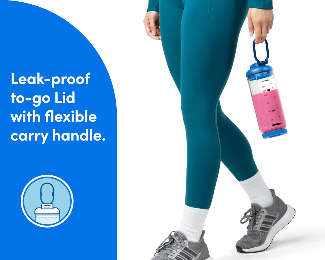 A woman's legs are shown walking in tennis shoes and teal athletic pants. Her hands are visible and she is carrying the sealed cup of the nutribullet Flex, filled with a bright pink smoothie, by the carry handle.