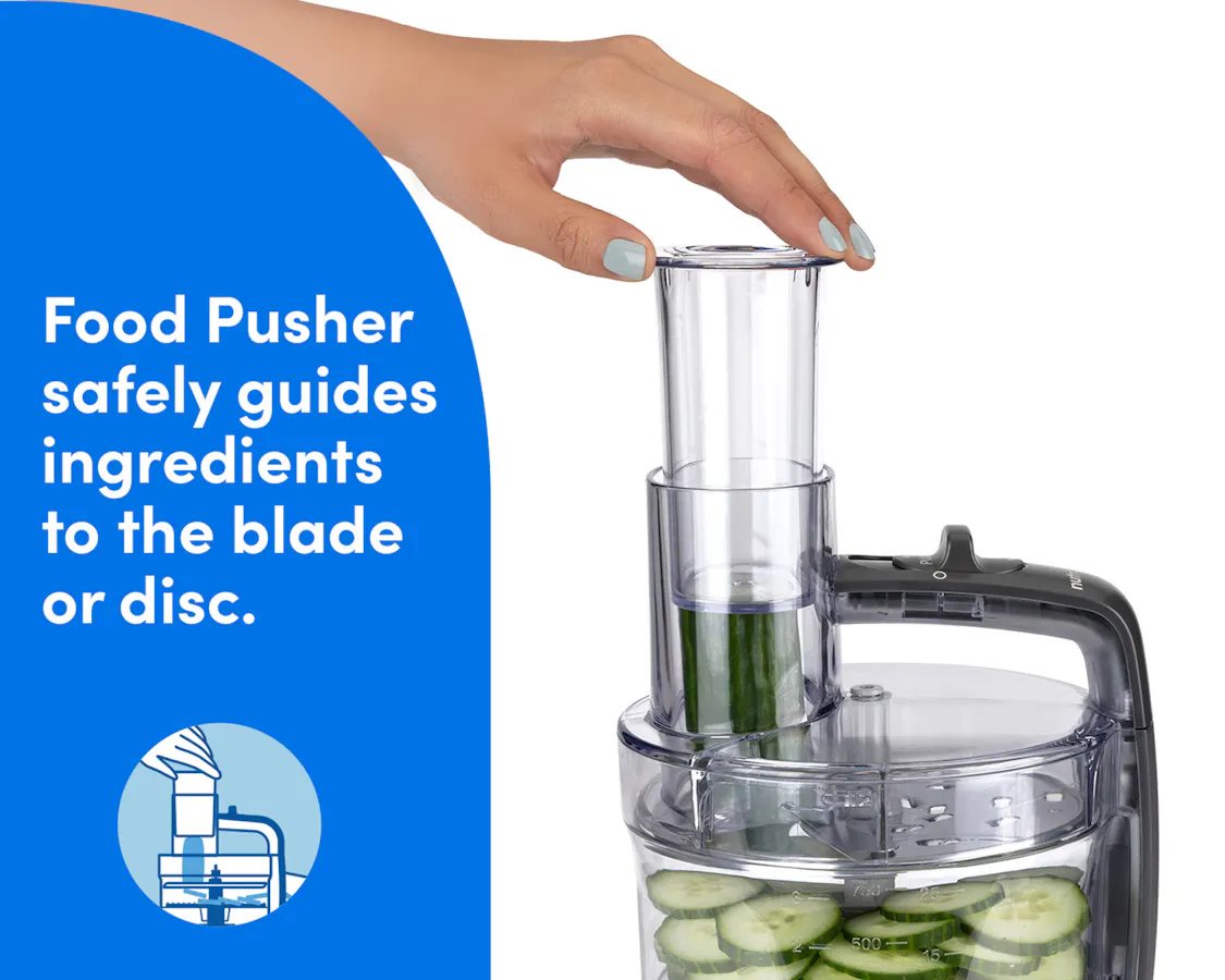 Hand using the food pusher on the nutribullet Limitless Food Processor to guide cucumbers into the slicing chute.