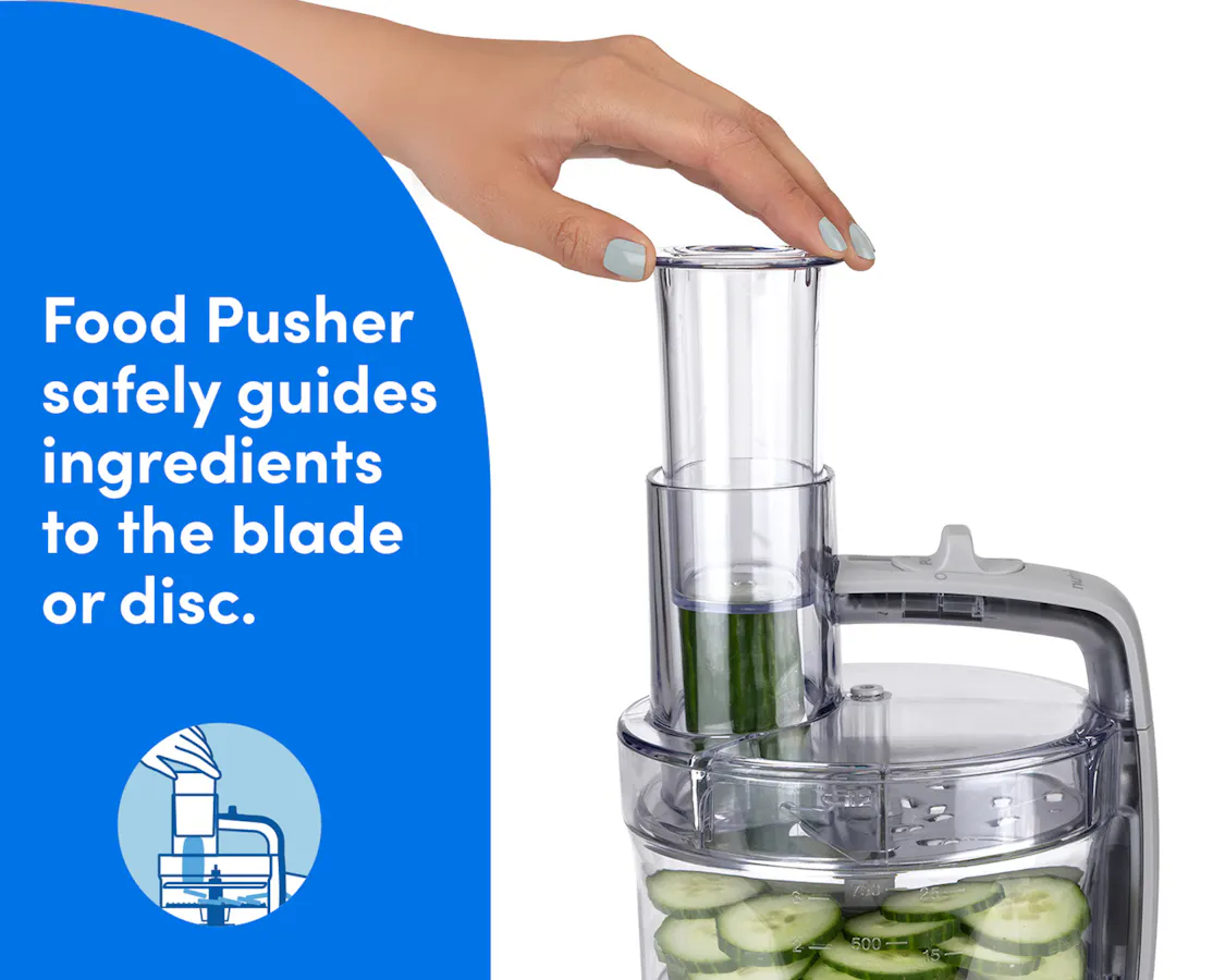 Hand using the food pusher on the nutribullet Limitless Food Processor to guide cucumbers into the slicing chute.
