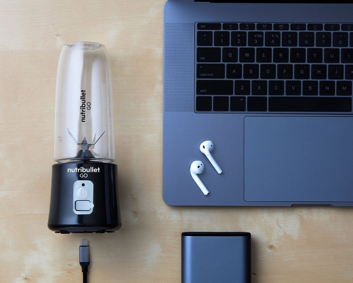 Black nutribullet GO with nutrition bar, laptop and headphones Black nutribullet GO shown with nutrition bar, laptop and headphones for size.