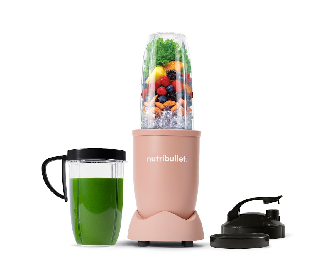 The full configuration of the nutribullet Pro rests on a white background. This includes the Power Base, Tall Cup, an extra Tall Cup with the Comfort Lip ring attached filled with a green smoothie, one extra Comfort Lip Ring, and two To-Go Lids.