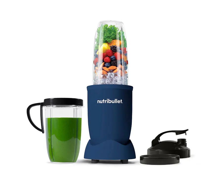 The full configuration of the nutribullet Pro rests on a white background. This includes the Power Base, Tall Cup, an extra Tall Cup with the Comfort Lip ring attached filled with a green smoothie, one extra Comfort Lip Ring, and two To-Go Lids.