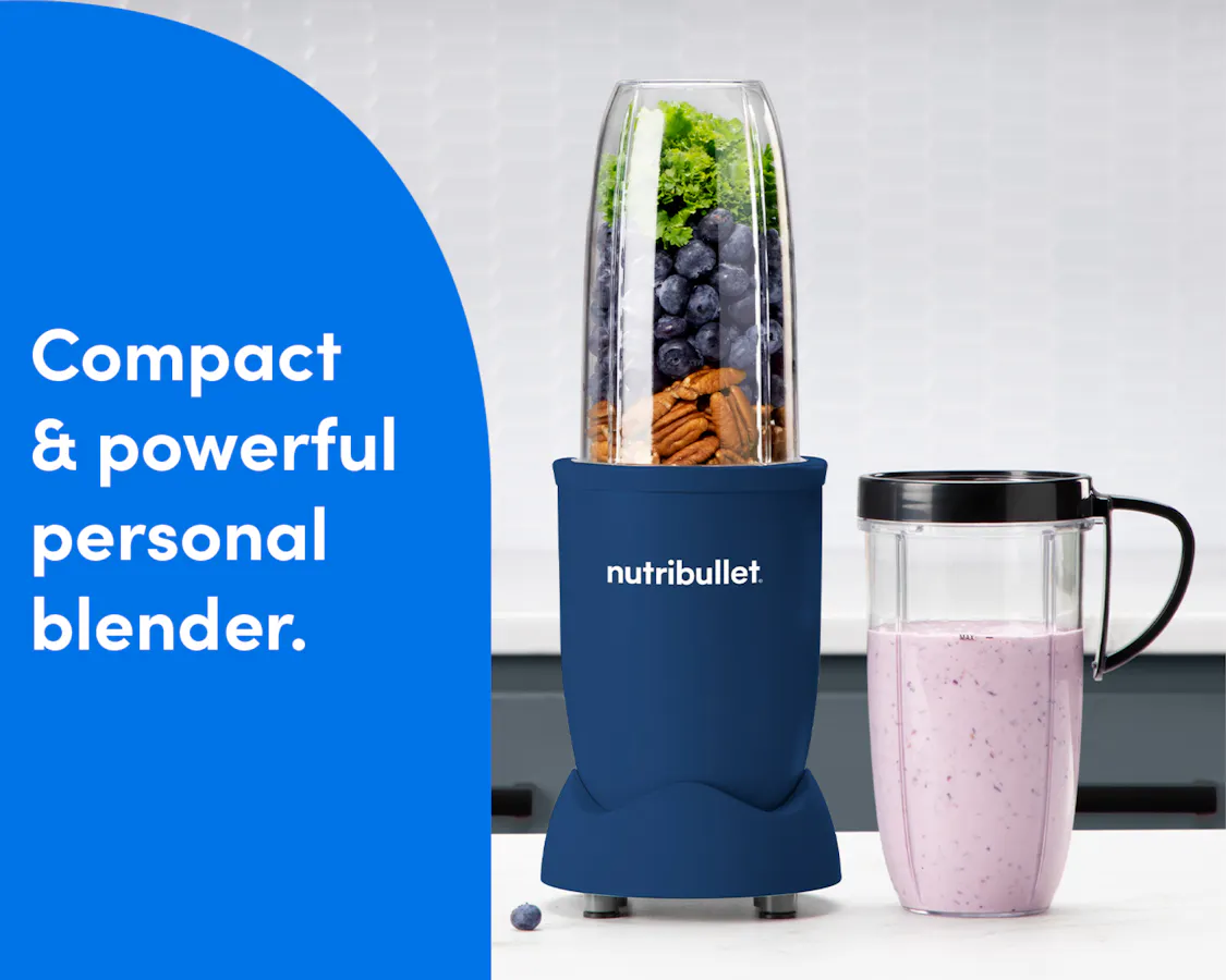The nutribullet Pro rests on a white countertop. The Tall Cup is attached to the Power Base and filled with a variety of unblended fruits and vegetables. A Tall Cup with the Handled Lip Ring attached rests to the right of the blender, filled with a light pink smoothie.