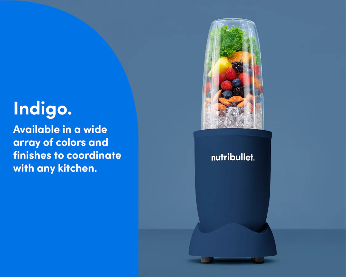 The nutribullet Pro in the color Indigo, from the Haven color collection, rests on a kitchen counter. The Tall Cup is attached to the Power Base and filled with fruit, ice, and nuts.
