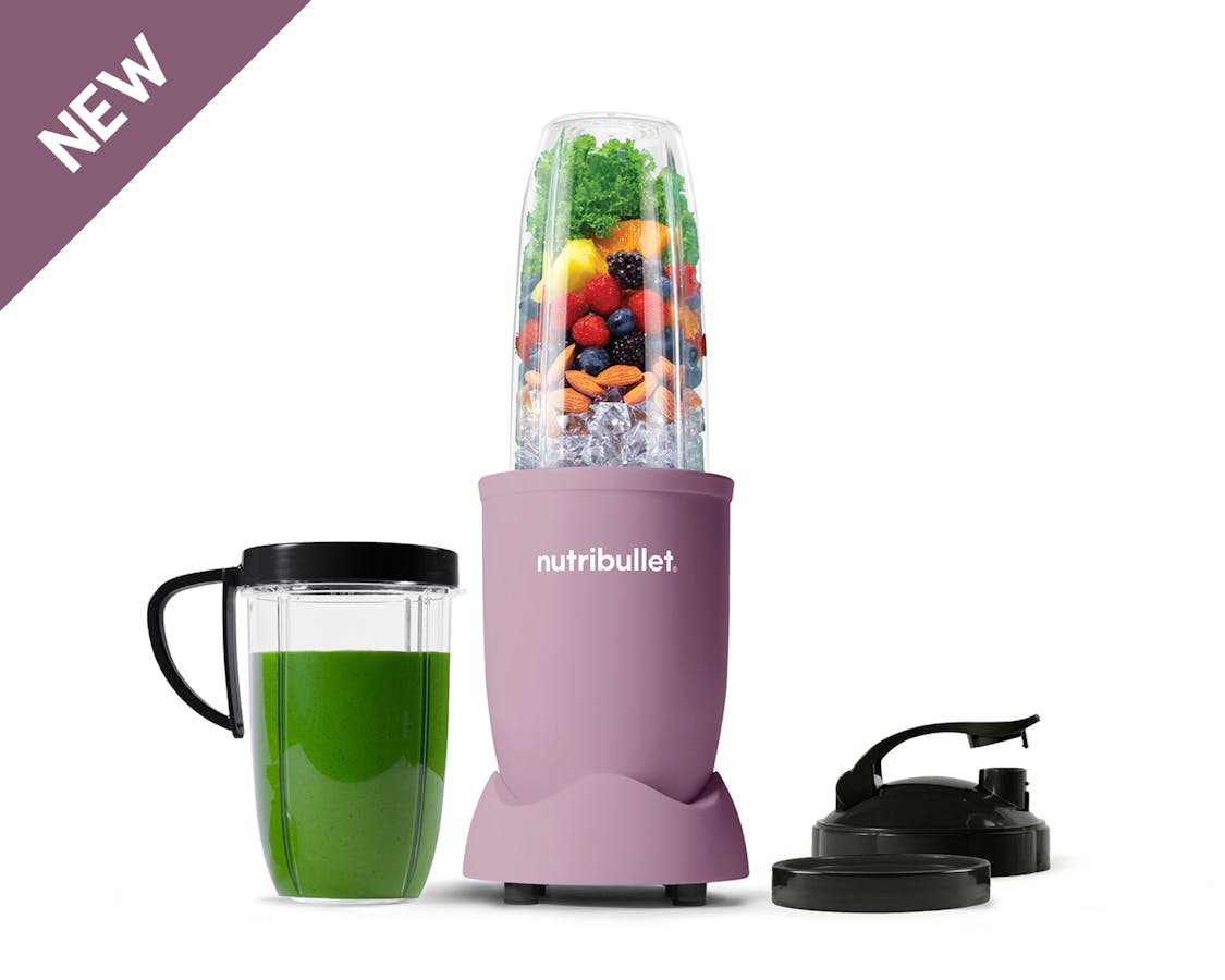 The full configuration of the nutribullet Pro rests on a white background. This includes the Power Base, Tall Cup, an extra Tall Cup with the Comfort Lip ring attached filled with a green smoothie, one extra Comfort Lip Ring, and two To-Go Lids.