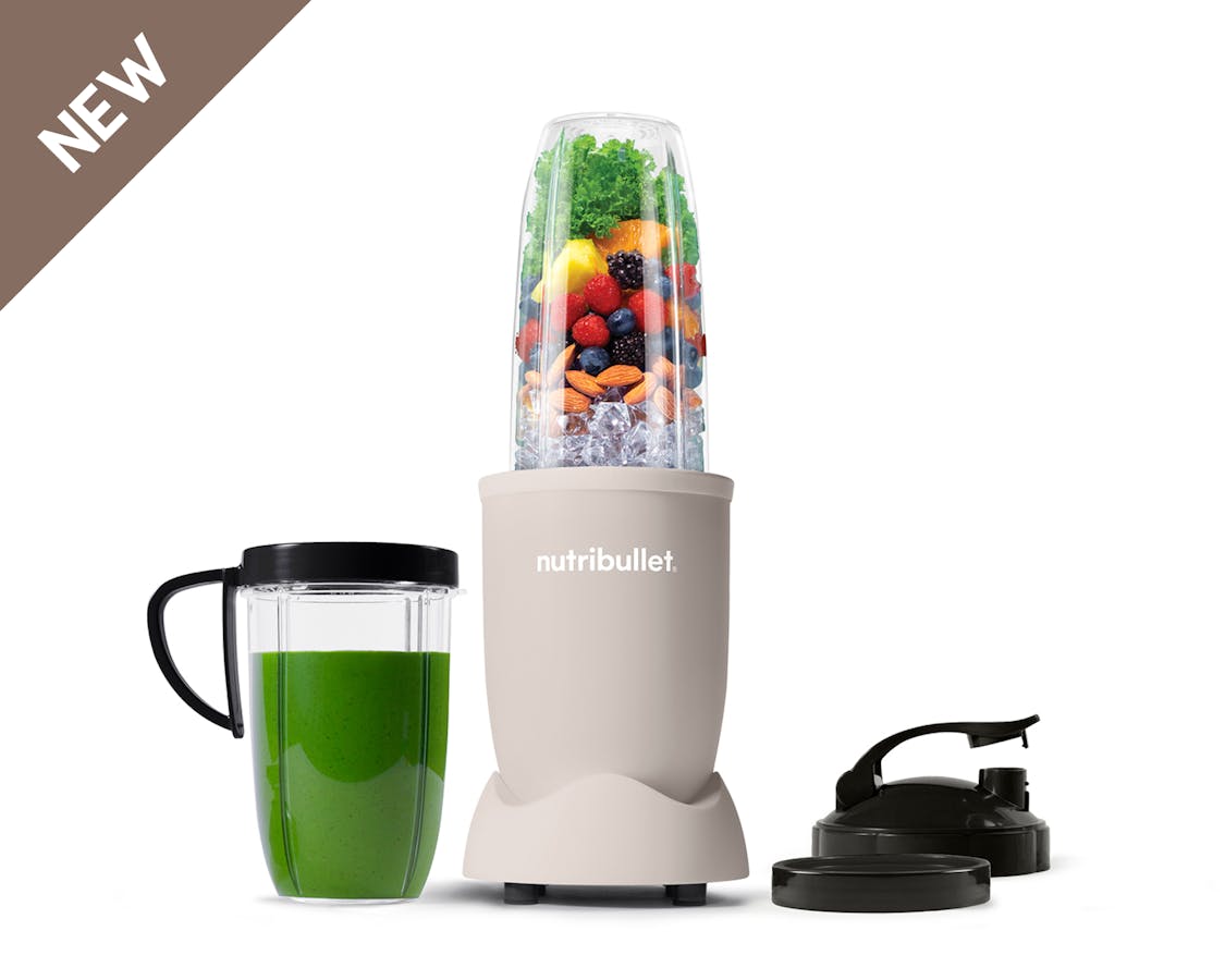 The full configuration of the nutribullet Pro rests on a white background. This includes the Power Base, Tall Cup, an extra Tall Cup with the Comfort Lip ring attached filled with a green smoothie, one extra Comfort Lip Ring, and two To-Go Lids.
