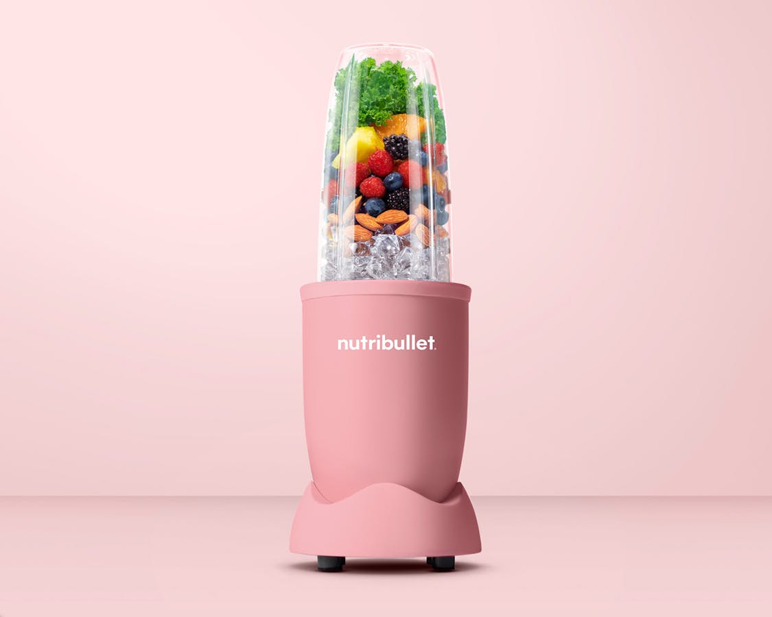Matte soft pink nutribullet pro 900 filled with ice, fruits and kale image.