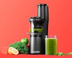 Product preview 1 of 8. Thumbnail of NEW black juicer filled with juice next to cup, fruits, veggies on orange background.