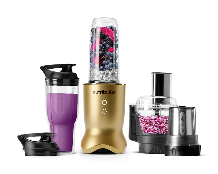 The brass-finish nutribullet Ultra Plus set with a sleek metallic base, a blending cup filled with fruits and ice, a travel cup with a lid, a food processor bowl, and a milling cup, all arranged on a white background.