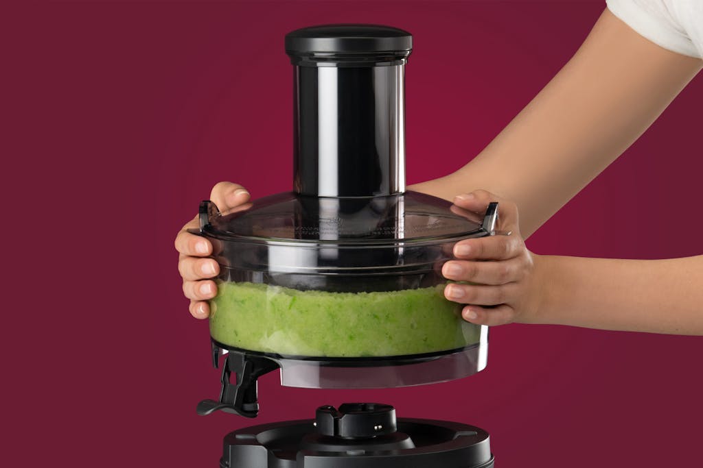 hands removing basin of fruit and vegetable pulp from the NutriBullet Juicer