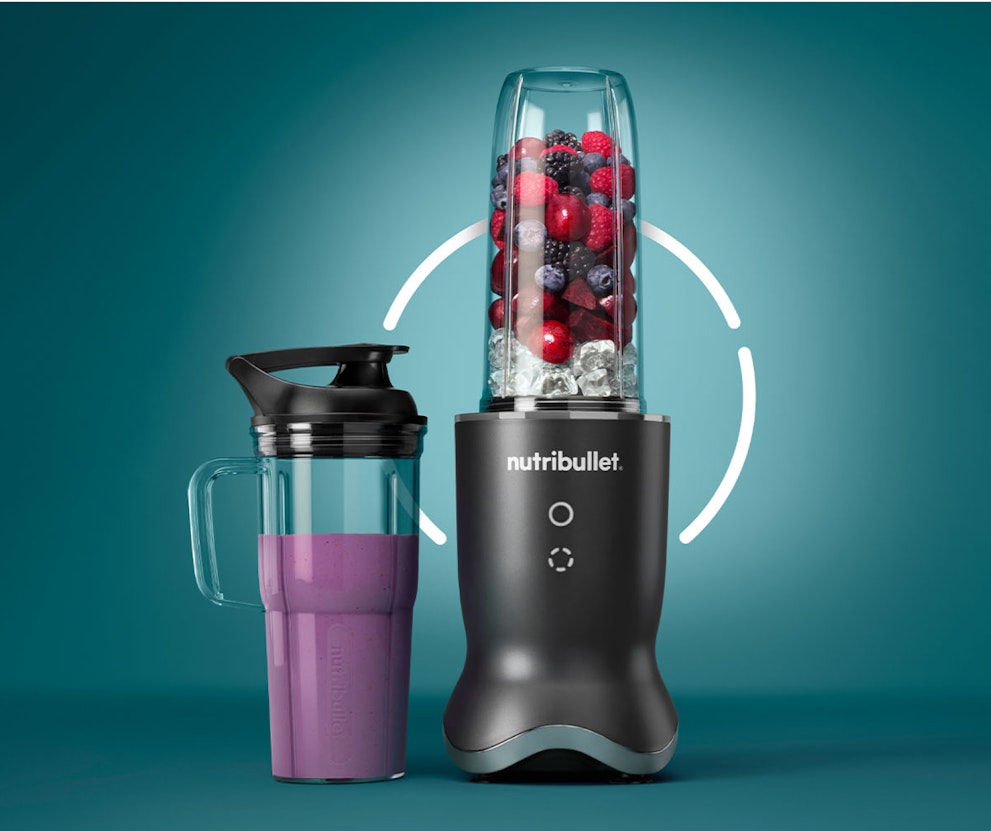nutribullet Ultra filled with fruits, sitting next to a smoothie.