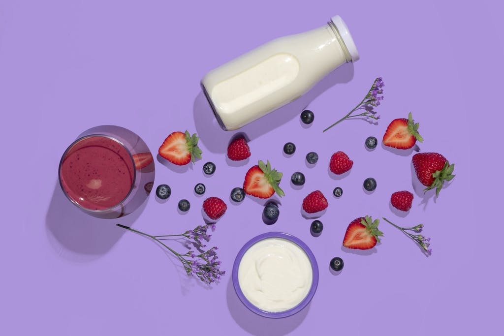berry smoothie flatlay with strawberries, blueberries, yogurt, and almond milk