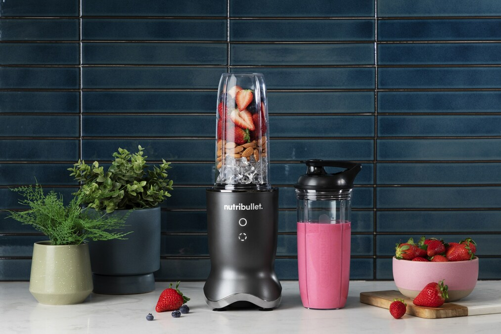 nutribullet Ultra filled with smoothie ingredients next to a blended pink smoothie 