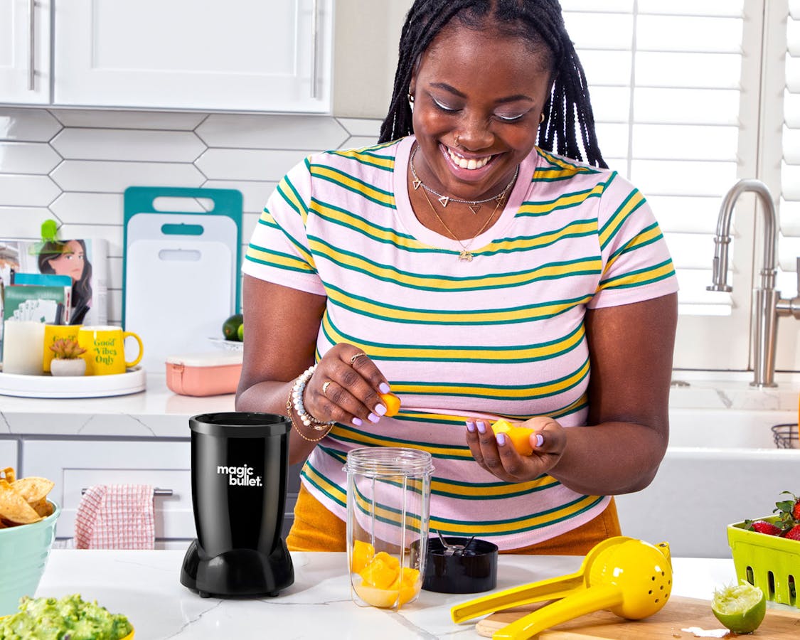 Woman making a smoothie to the black magic bullet blender in the kitchen
