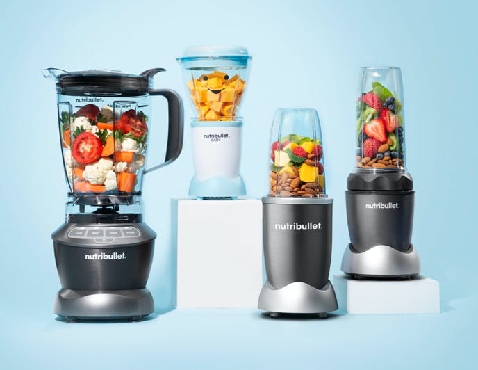 Selection of four nutribullet blenders with two on white pedestals on light blue background.
