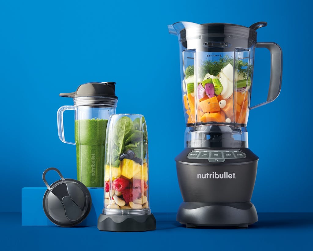 nutribullet Blender Combo with fruits and vegetables on blue background.