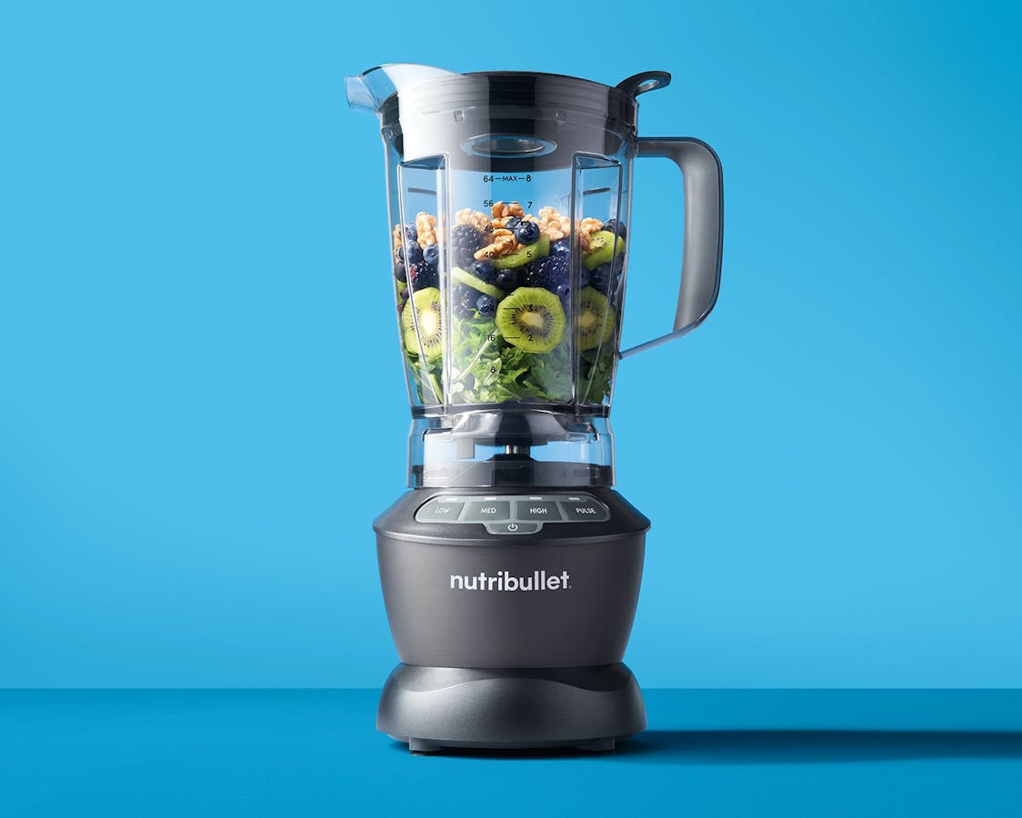 nutribullet Blender with fruits, vegetables, and nuts on blue background.