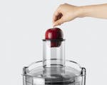 Product preview 6 of 7. Thumbnail placing apple in juicer chute on grey background.