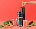 Product preview 2 of 8. Thumbnail of juicer with carrot in chute next to cups, fruits, veggies on orange background.