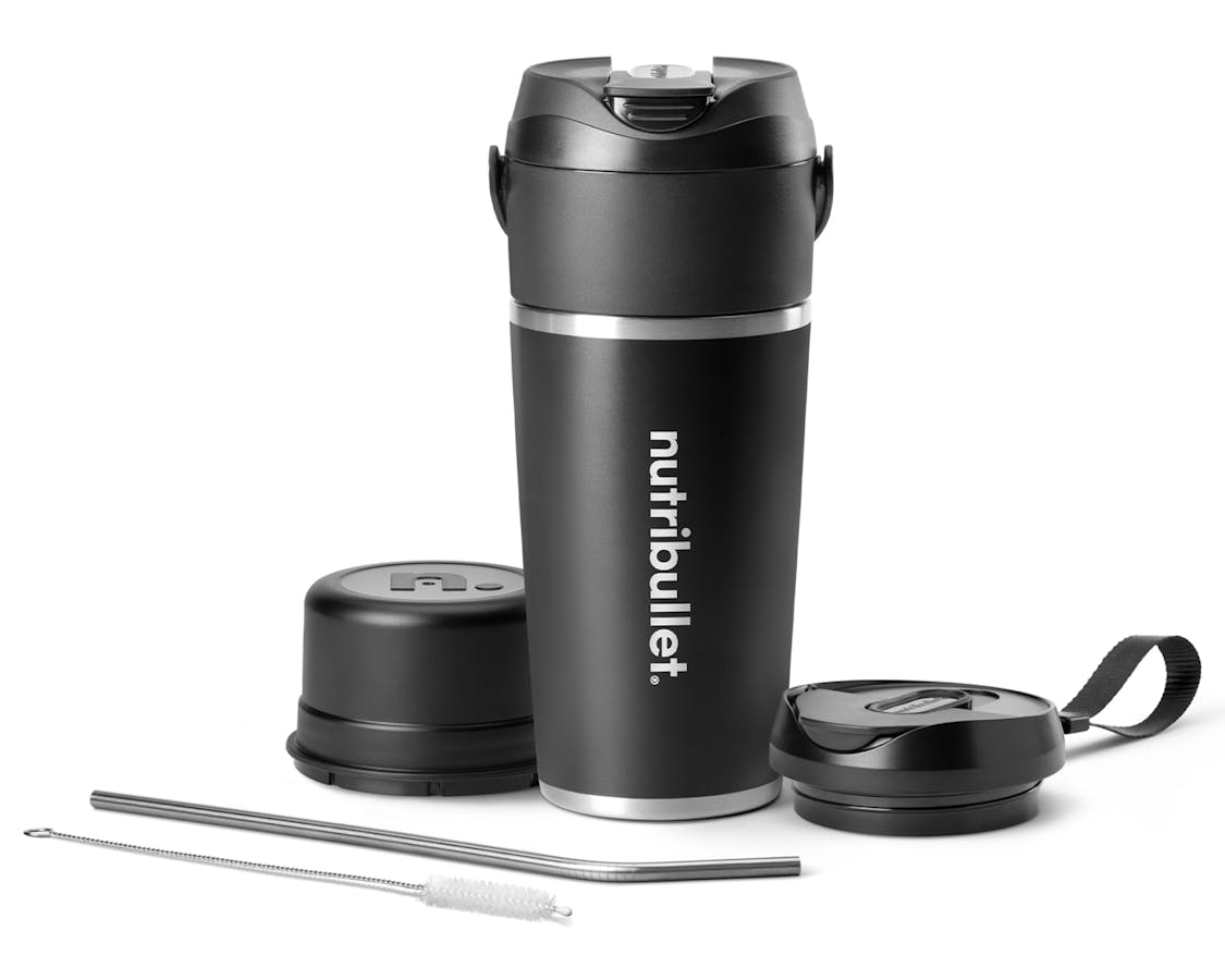 nutribullet Flip full configuration. The black insulated tumbler is shown with the sip-through blade attached at the top. The blade cover rests to the left of the tumbler, and the to-go lid is situated to the right. A metal straw and straw-cleaning brush rest in front of the tumbler at an angle.