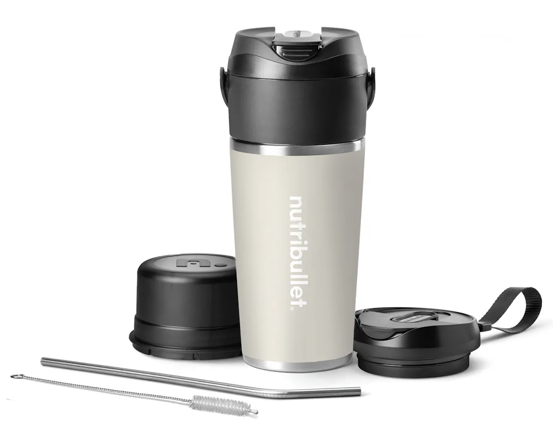 nutribullet Flip full configuration. The Linen insulated tumbler is shown with the sip-through blade attached at the top. The blade cover rests to the left of the tumbler, and the to-go lid is situated to the right. A metal straw and straw-cleaning brush rest in front of the tumbler at an angle.