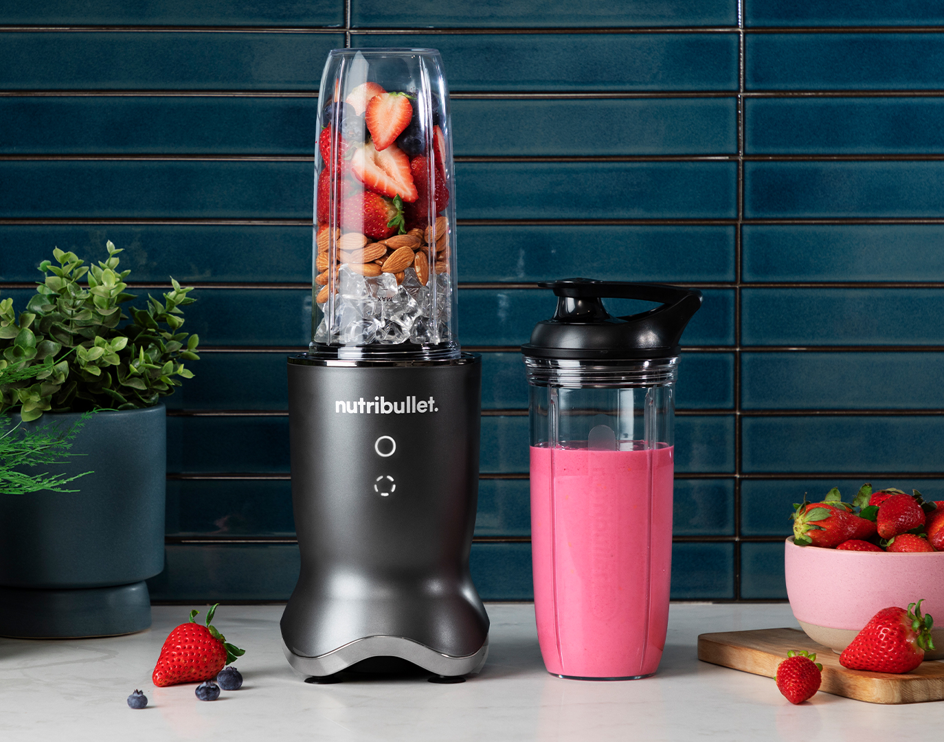 black nutribullet Ultra filled with smoothie ingredients next to a blended pink smoothie